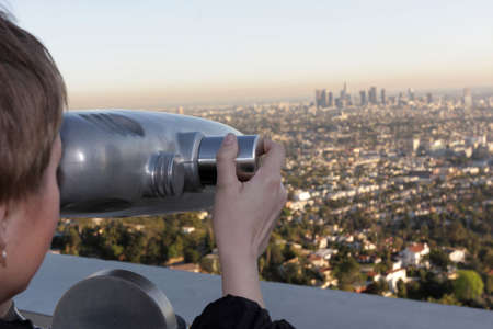 The girl views Los Angeles by telescopeの写真素材