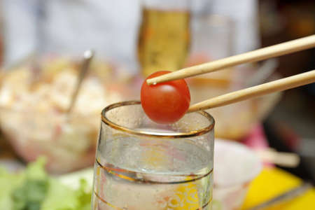 The cherry tomato with a chopsticks and glasses of water の写真素材