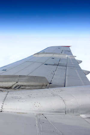 The silvery wing of a airliner in the sky