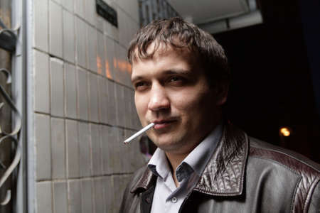 The smoking man in leather coat outdoor