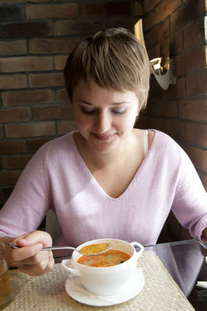 The woman eats soup in a restaurantの写真素材