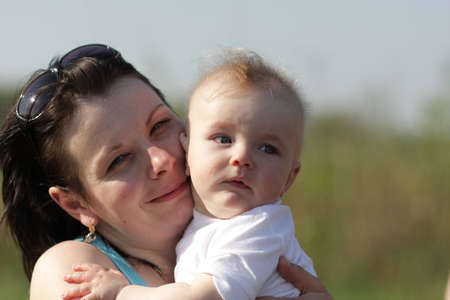 The mother embraces her baby outdoor at summerの写真素材