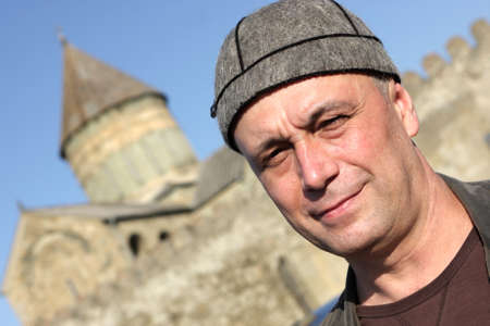 The man poses in national georgian hat on church background in Georgiaの写真素材