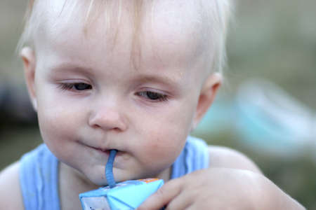 The baby drinks a juice by straw outdoorの写真素材