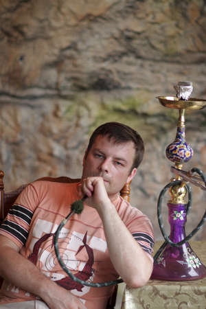 The man is smoking shisha in arabic restaurant