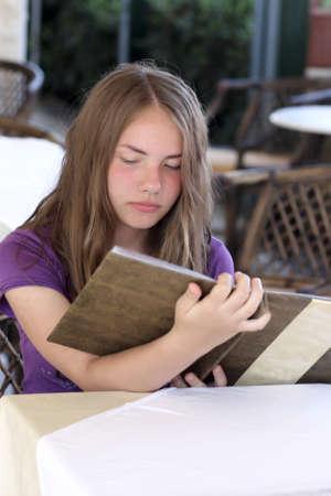 The teen reads a menu in the cafeの写真素材