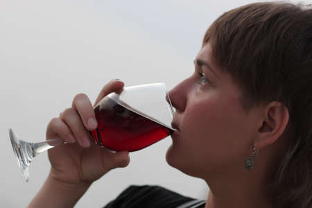 The woman drinks red wine outdoor in the eveningの写真素材