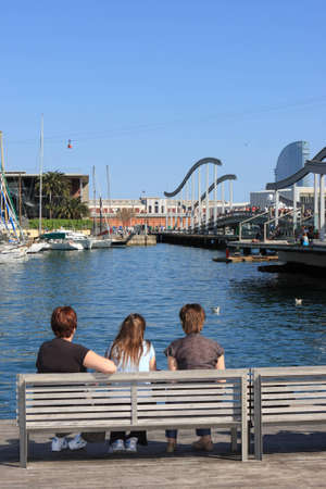 Resting three women sit on the bench in harbor of Barcelonaの写真素材