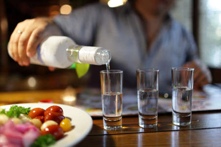 man pouring vodka in the pub in the evening