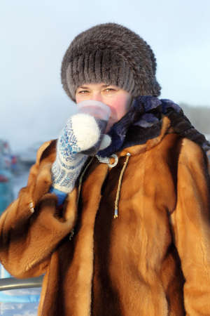 The woman drinking hot tea outdoor in winter, Siberia, Russia