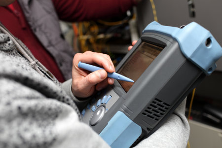 Telecom technician holding reflectometer of fibre optic at server roomのeditorial素材