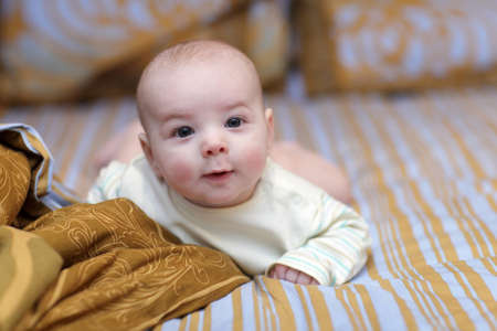 The surprised baby lying on a bed at home