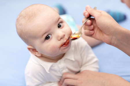 A mother giving a spoon of iron syrup to her baby