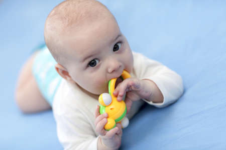 The baby boy with a rattle on a blue sheet