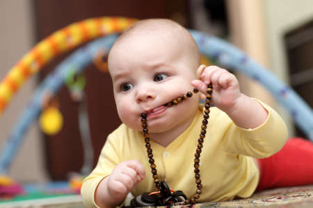The funny baby sucking beads at home