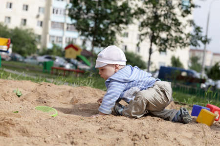 Little child is crawling in sandbox at playgroundの写真素材