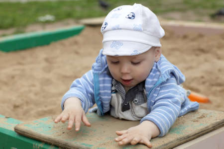 Toddler is playing in sandbox at playground