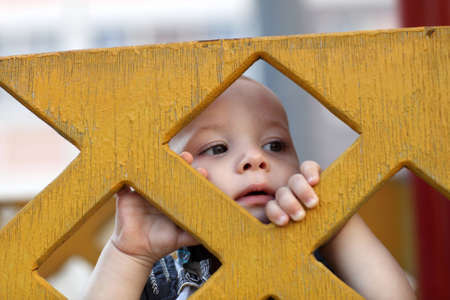 Child is behind yellow wooden fence at playgroundの写真素材