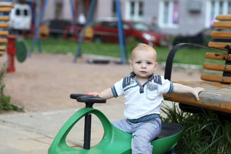 Toddler is posing on toy car at playgroundの写真素材