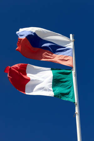 Russia and Italy national flags are waving on the sky background