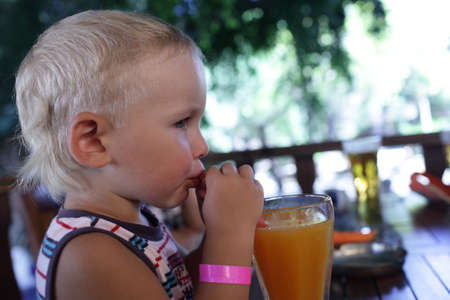 Boy is drinking fresh orange juice in a restaurantの写真素材