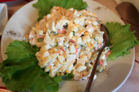 Salad with crab sticks and eggs on a white plateの写真素材
