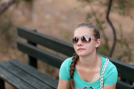 The tired teen is resting on a benchの写真素材