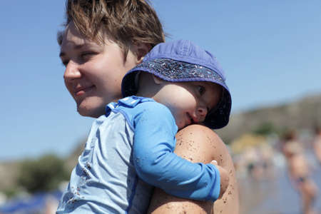 Mother holding her toddler on a beach of Faliraki, Rhodes, Greeceの写真素材