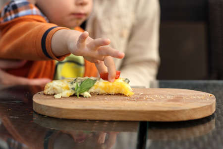 Toddler takes slice of tomato from a bruschetta in a restaurantの写真素材
