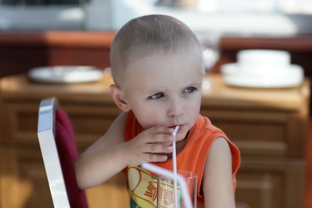 Serious child has juice in a cafeの写真素材