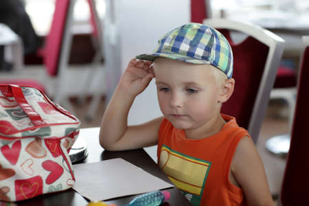 Pensive child is at the table with a paperの写真素材