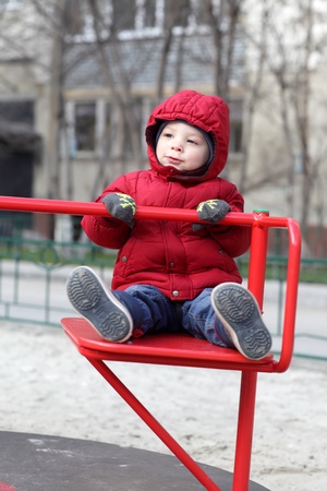 Boy is playing at outdoor playground in autumnの写真素材