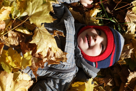 Child is lying on leaves in the autumn parkの写真素材