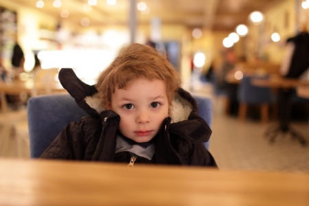 Portrait of pensive toddler at table in cafeの写真素材
