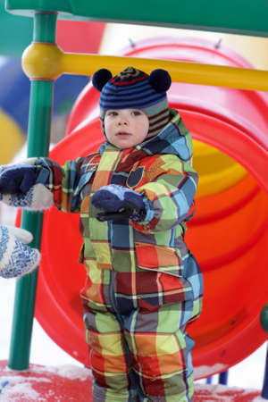 Serious child is at playground in winter