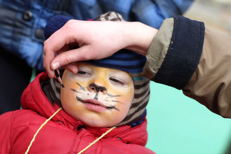 Child being face painted into a tigerの写真素材
