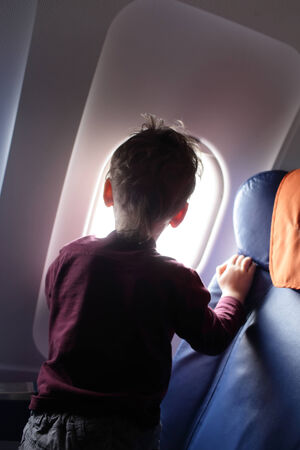 Curious boy looking through window in the airplaneの写真素材