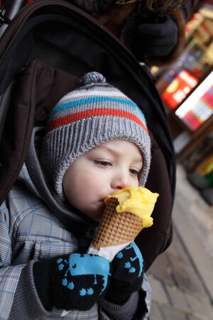 Child eating ice cream on the street in cityの写真素材