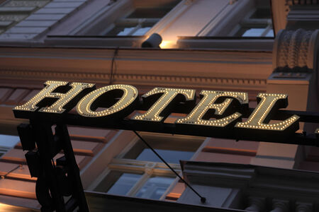 Illuminated yellow hotel sign on the wall of buildingの写真素材