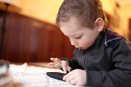Boy playing on the smartphone in the restaurantの写真素材