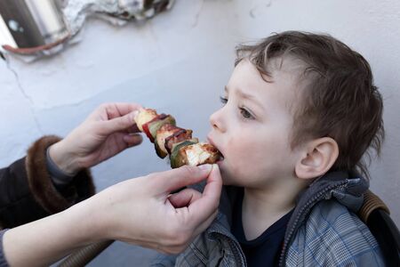 The boy eating kebab in the restaurantの写真素材