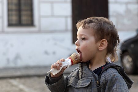 Boy with ice cream cone on the streetの写真素材