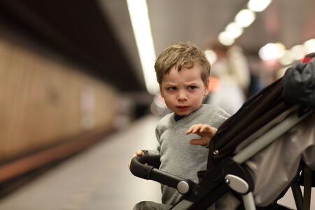 Sullen boy on a stroller at subway stationの写真素材