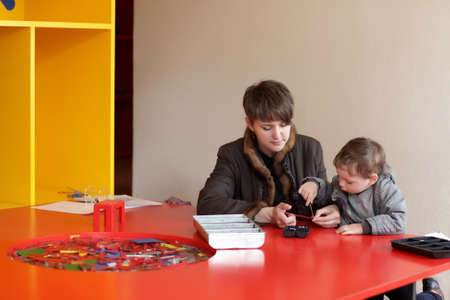 Mother and her son play with the vintage construction set at house