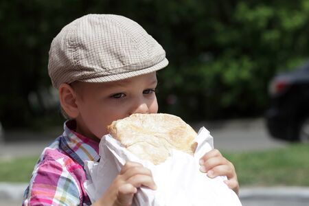 Child eating big loaf of bread in the parkの写真素材