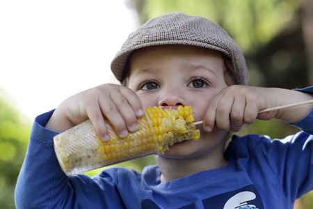 Hungry kid eating corn in the parkの写真素材