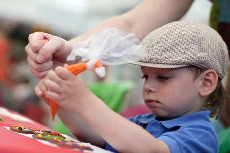 Child painting gingerbread shapes with a food coloringの写真素材