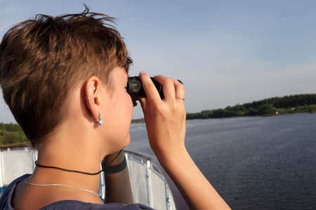 Woman looking through binoculars on Volga riverの写真素材