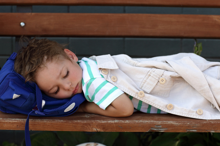 The sleeping boy on the wooden bench