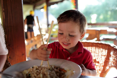The kid eating noodles in an asian restaurantの写真素材